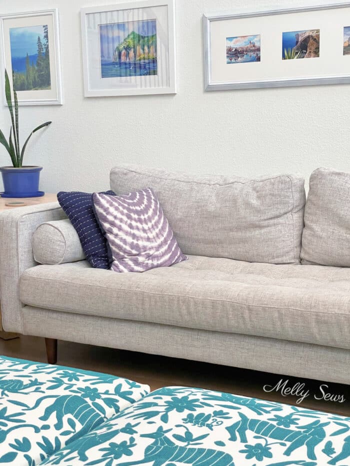Light gray mid century modern style couch with otomi print ottomans in foreground
