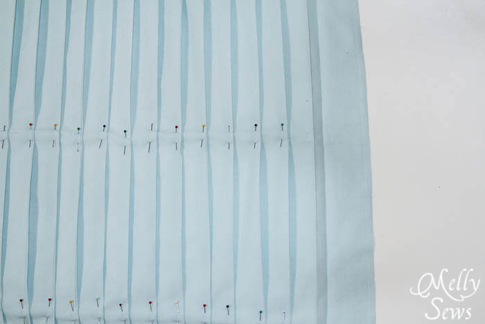 Pressed and pinned pleats on light blue fabric 