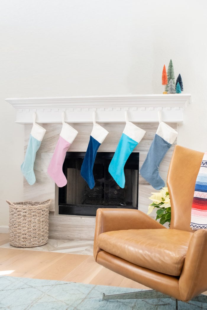 Green, pink, navy, turquoise and gray velveteen Christmas stockings in a colorful row