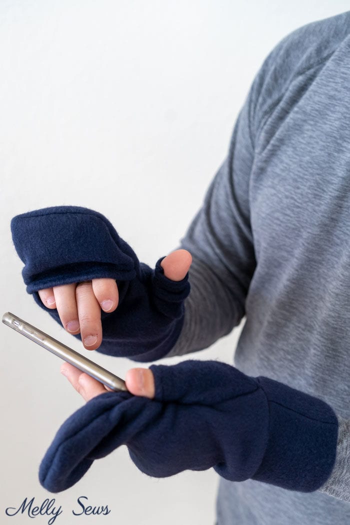 Man using phone while wearing navy fingerless mittens