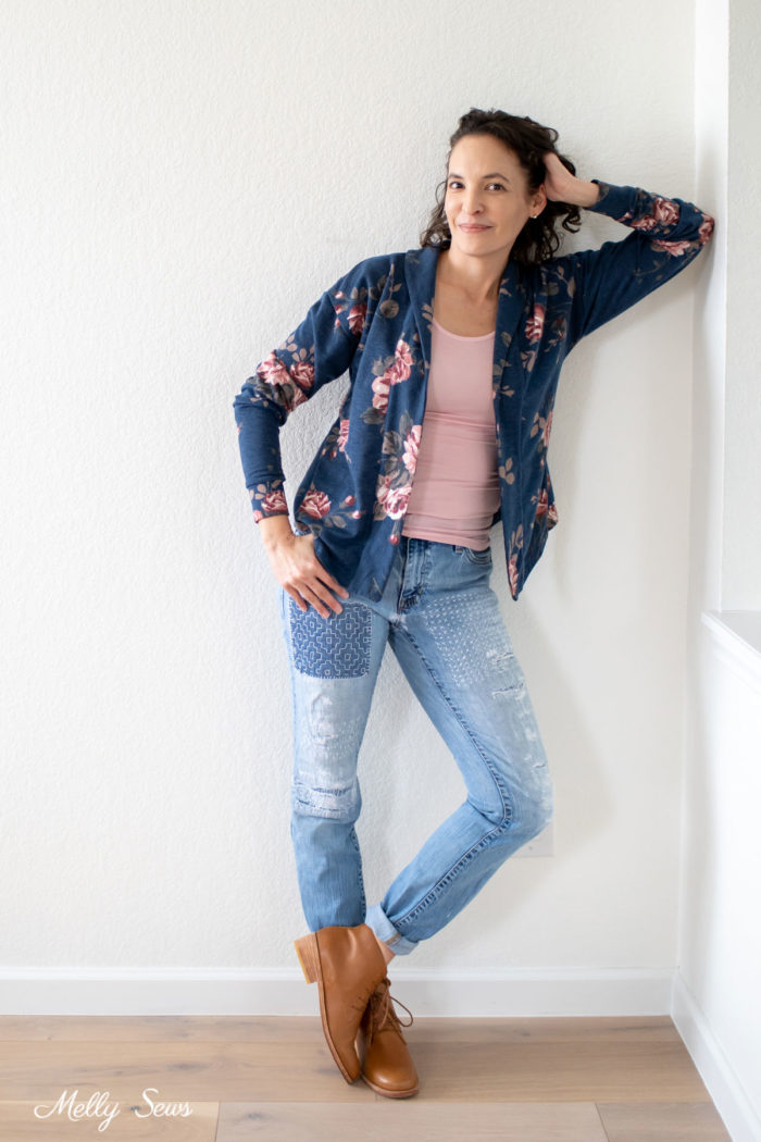 Woman wearing a floral cardigan, tank and mended jeans outfit with lace up ankle boots