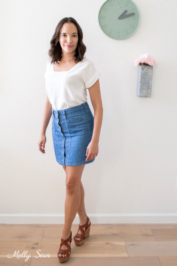 Brown haired woman wearing a self sewn outfit of a white blouse and denim skirt