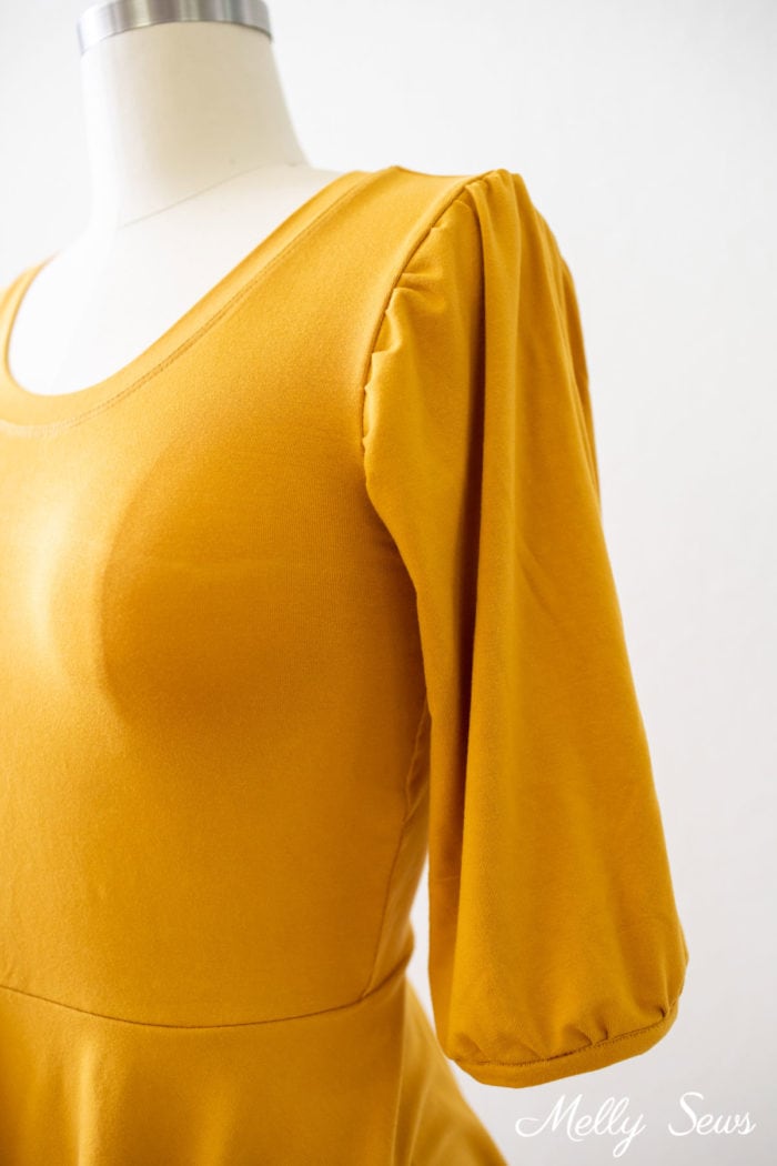 Puff sleeve detail on a gold peplum blouse