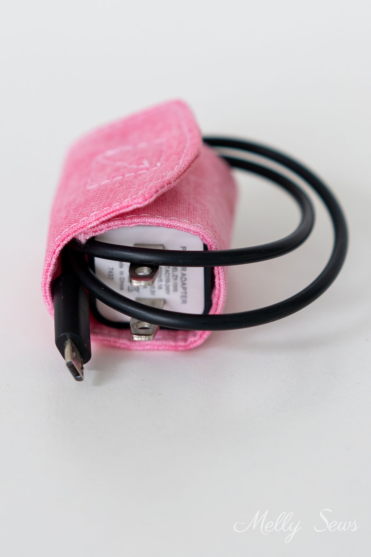 Pink cord keeper wrapped around a charger cord and brick
