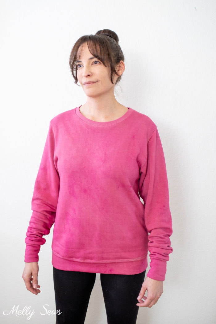 Pink hand dyed sweatshirt worn with black leggings by a Latina woman