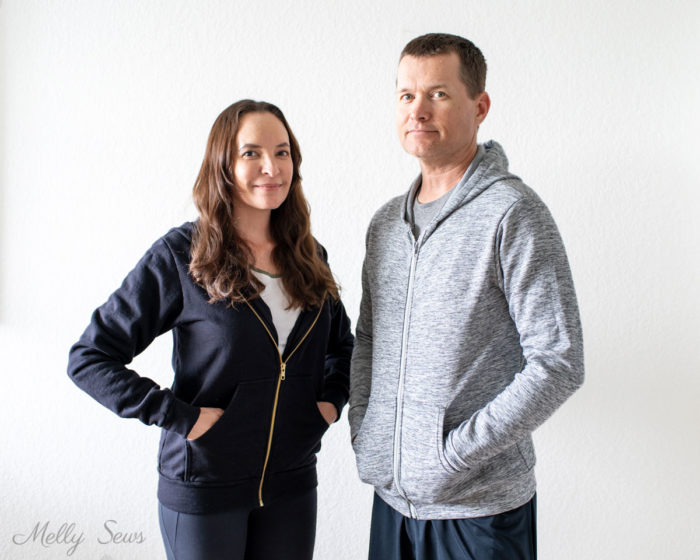 Woman in a black zip up hoodie stands next to a man in a gray zippered hoody