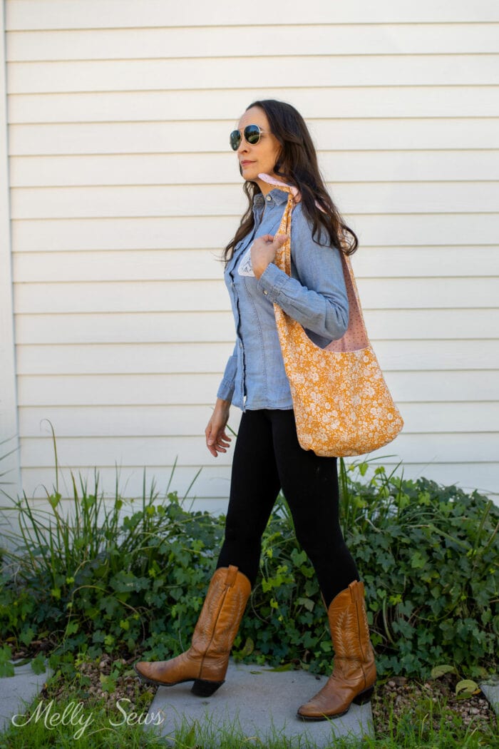 Woman in leggings, boots and chambray shirt carrying a handmade reversible cotton purse