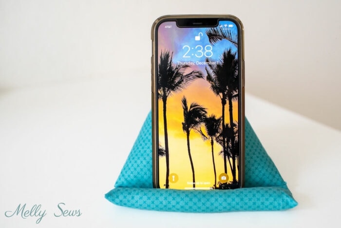 iPhone standing vertically supported on a pillow designed to hold it