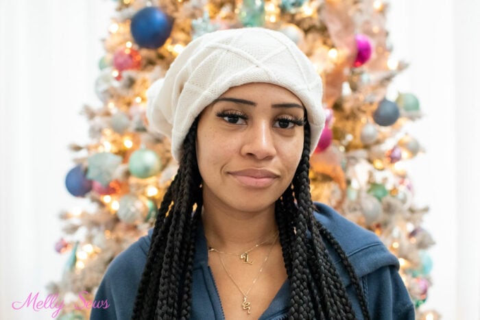 Black Girl with braids wearing a beanie hat with a pom pom