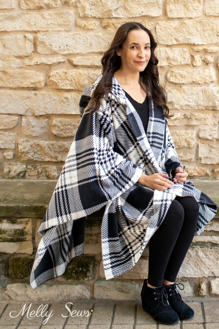 Seated woman wearing a black and white plaid poncho with a hood
