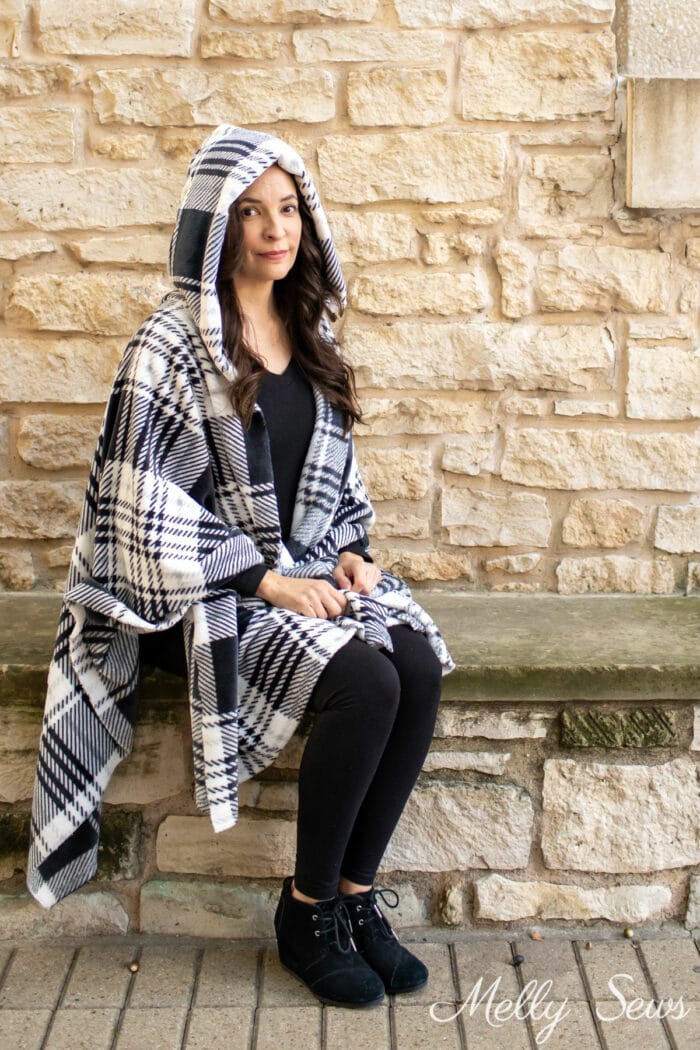 Woman wearing a plaid hooded poncho while seated