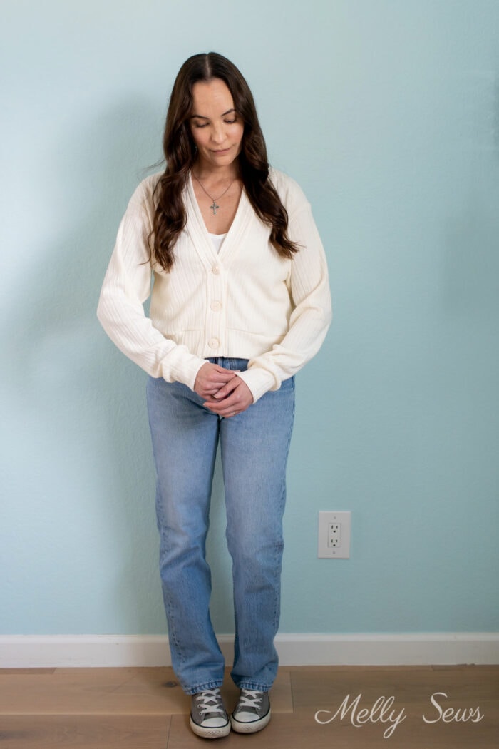 Woman in faded jeans and an ivory cropped cardigan she made