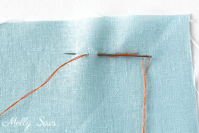 How to sew a backstitch - orange thread on blue fabric demonstrating a back stitch