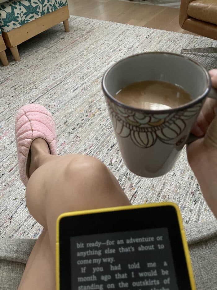 Kindle book, coffee mug, woman's foot with concha slipper in background