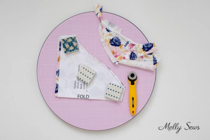 Round pink cutting mat with a rotary cutter and pattern piece on top