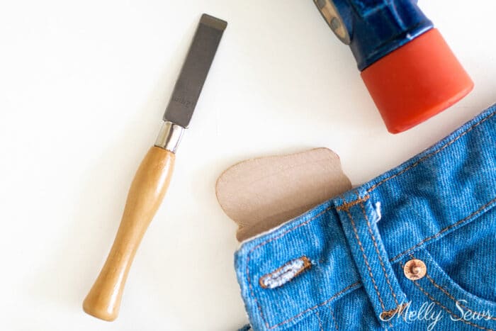 Buttonhole chisel next to a mallet head and a pair of jeans