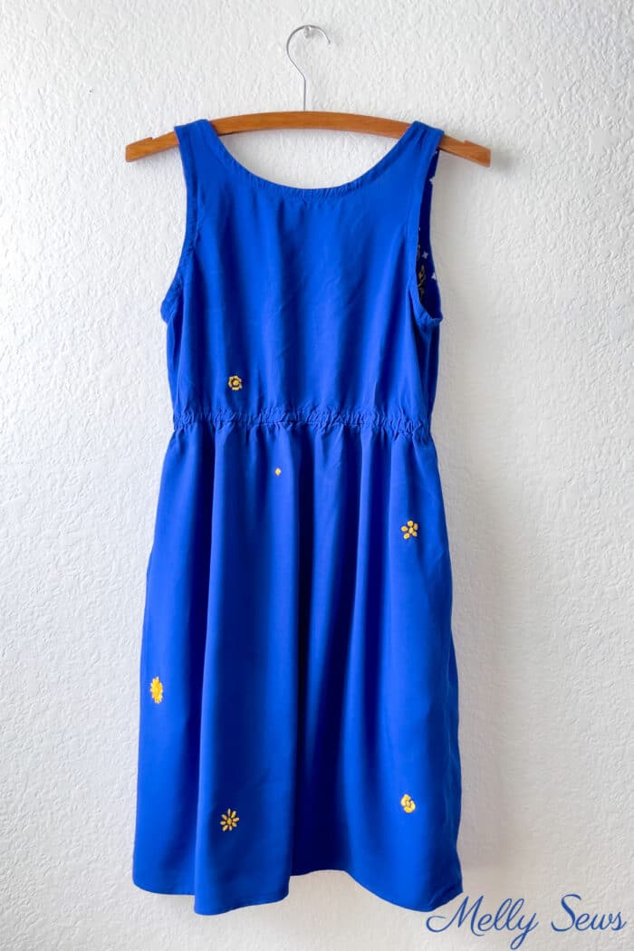 A blue dress has gold embroidery over holes in the fabric