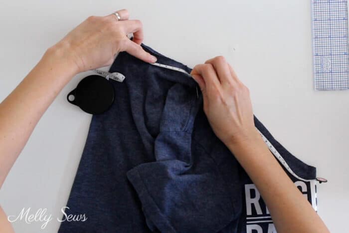 Hands measuring the neckline of a t-shirt to determine neckband length