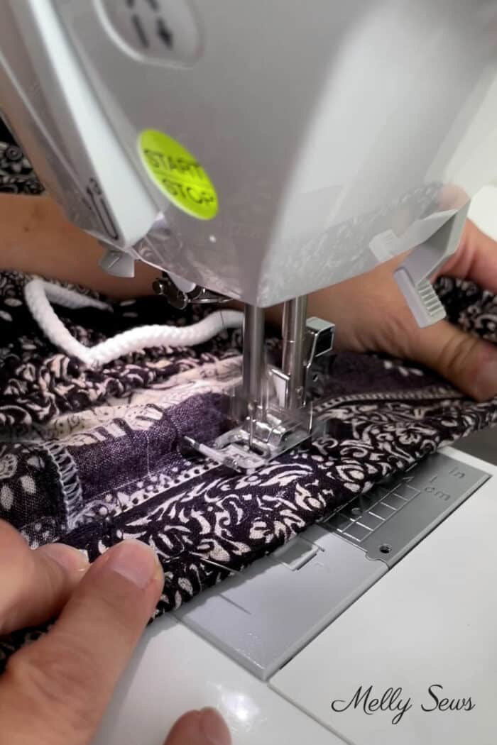 Hands stretching a waistband on a sewing machine to sew casing closed