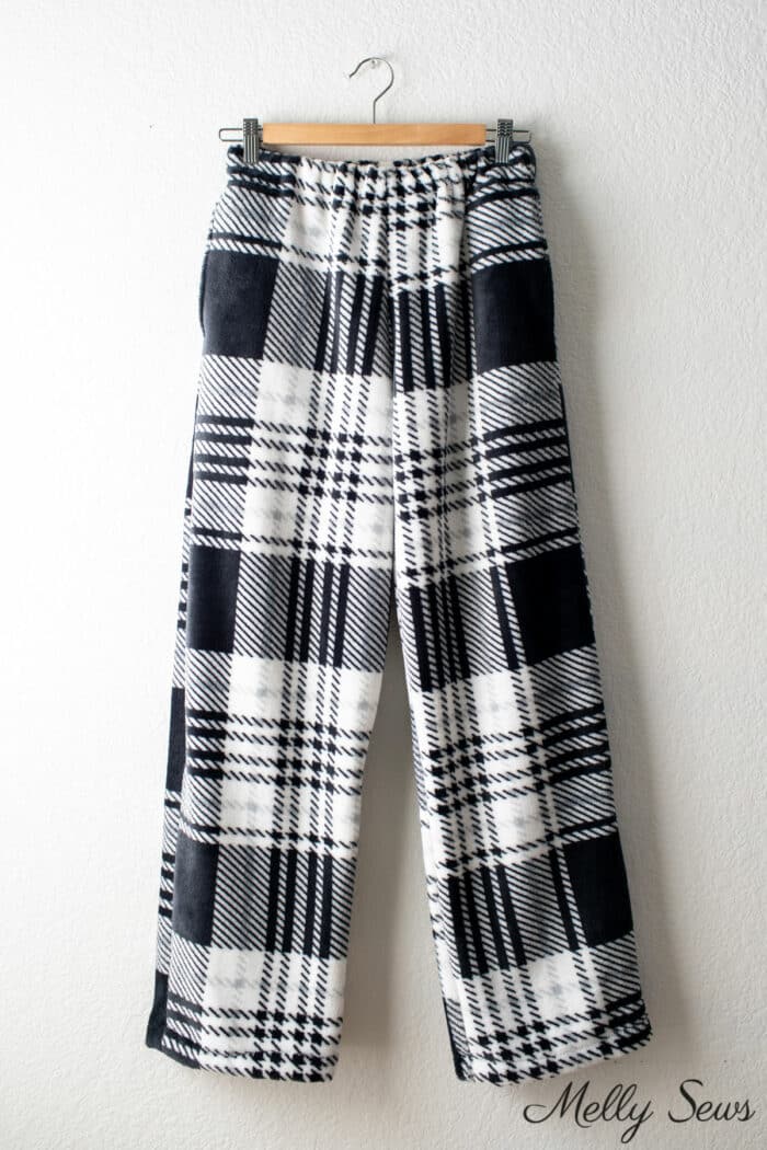 Fuzzy black and white pj pants sewn at home and hanging on a hanger in front of a white wall