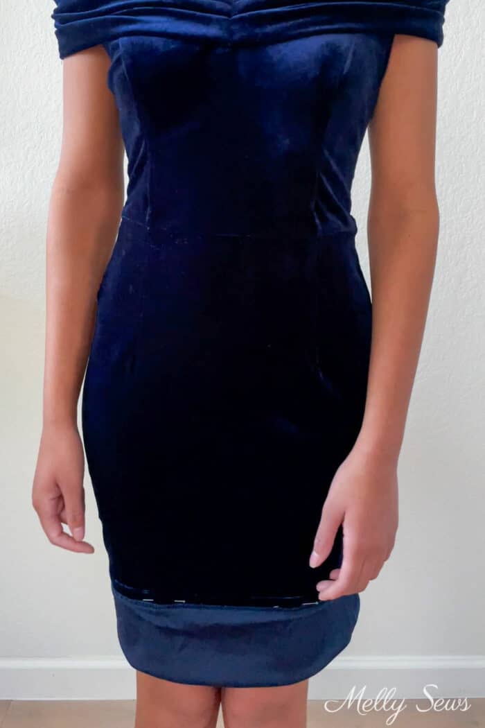 Woman's body in a basted blue dress with the hem pinned up