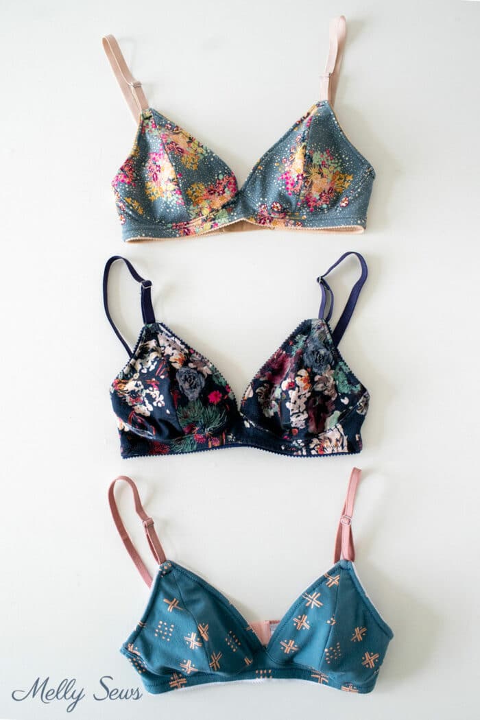 Gray floral, blue and coral abstract print and navy blue floral bras on a white table