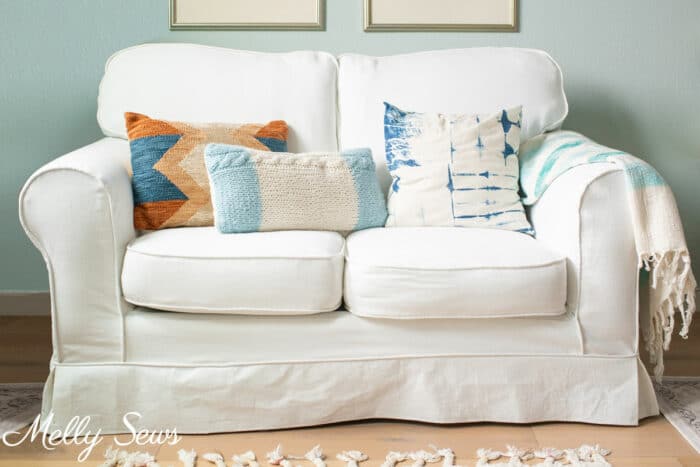 White canvas slipcovered couch with blue, aqua and rust pillows