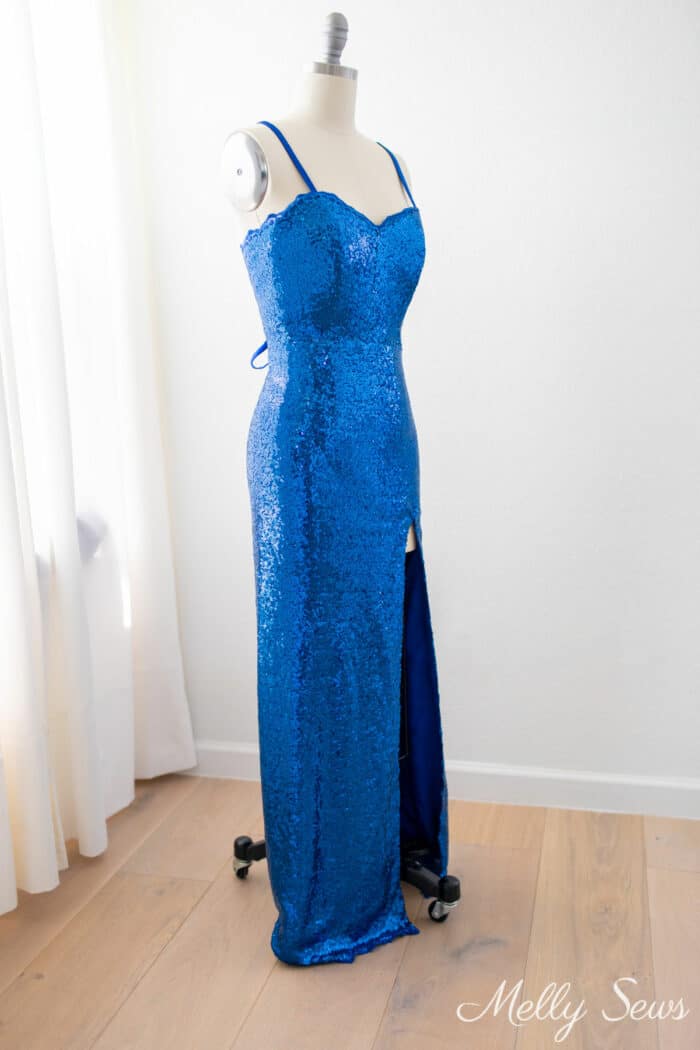 Blue form fitting dress with a high slit on a dress form