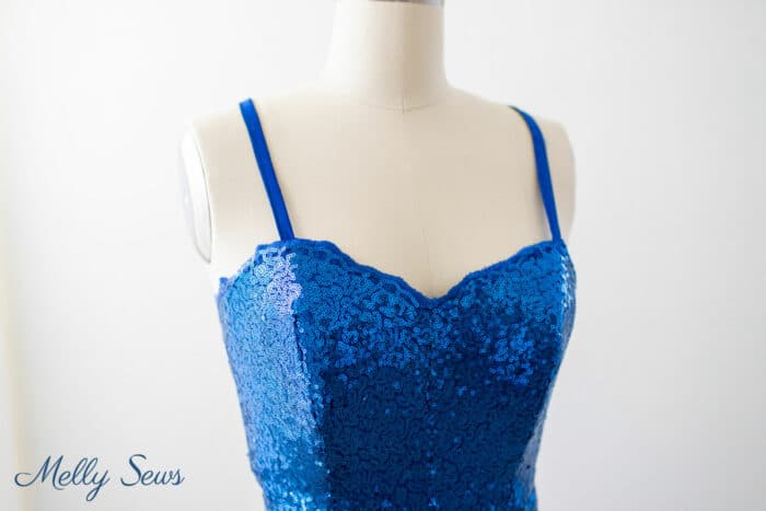 Close up of sweetheart bodice in blue sequins with a scalloped, embroidered edge